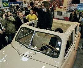 Inter auto 2005 international motor show, actor leonid yarmolnik greets visitors as he stands in his 1954 pobeda (ussr), crocus expo center, moscow, russia, 2005.