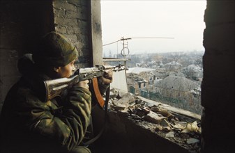 Second chechen war, a russian machine gunner in a firing position in a half-ruined building in the stanopromys district of grozny, checnya, january 2000.