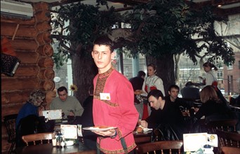 Waiter in traditional russian shirt waiting tables at yolki-palki russian-style fast food restaurant, moscow, russia, 2000.