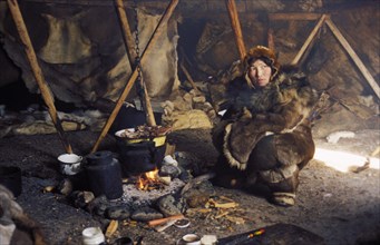 A chukchi woman in her tent cooking meat in chukotka, siberia, russia, 2000.