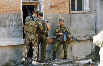 Members of the russian rapid action police (sobr) doing a house to house search during a three hour battle with chechen militants in grozny, chechnya, may 2000, writing on the wall reads: 'people live...