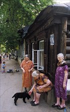 Elderly women in front of an old wooden house in a district in samara built in the19th century, russia.