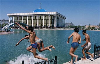 Boys swimming in a pool of a new park near the parliament building (in the background) in tashkent, uzbekistan, 1990s.