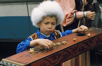 Young boy playing a dulcimer like musical instrument at the tun-pairam festival in khakassia, siberia, july 1998.