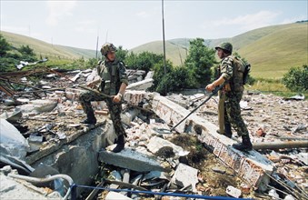 Russian peacekeepers using metal-detectors to search for unexploded bombs on the site of a yugoslavian ammunition depot destroyed in a nato air attack outside the slatina airport in pristina.