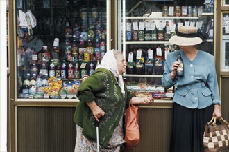 A woman beggar by a kiosk on a moscow street, august 1999.