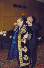 Uzbek president islam karimov helping rf president vladimir putin put on a traditional robe, uzbekistan, december 1999.