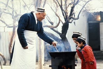 A grandfather with his grandsons, cooking rice pilaf, uzbekistan, 1990s.