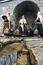 Women in traditional dress getting water from a well in lagich, azerbaijan, 1990s.