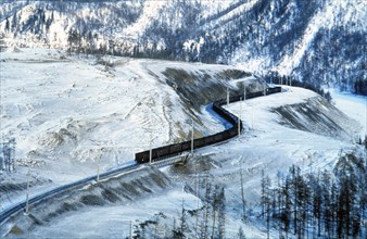 A freight train traveling along the trans-siberian railway through a snowy landscape in winter, siberia, russia.