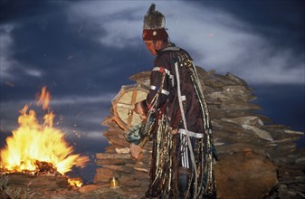 A tuvan shaman by a fire, communing with spirits, tuva, russia.