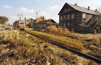 A trolley going past old wooden houses on atypical street in astrakhan, russia.
