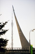 The monument to the explorers of space (space obelisk) at vdnkh with the ostankino television tower in the background, moscow, russia, 2004.