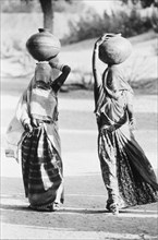 Two ladies, faces covered off to the well to fetch water , Rajasthan , India