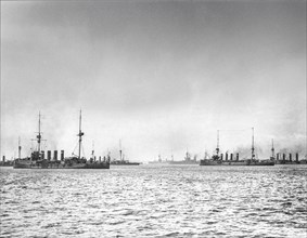 Historic black and white image of ships on the ocean under a cloudy sky
