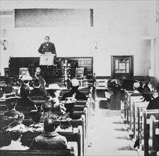 Black and white historic image of a preacher in a pulpit and the congregation in the wooden pews