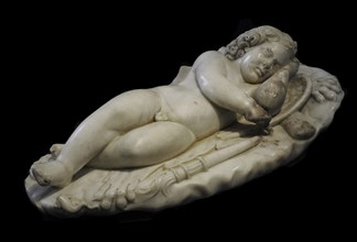 Statue of God Eros child reclining and asleep on a rocky surface