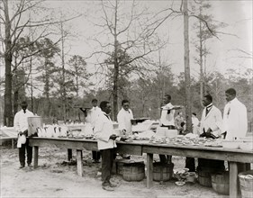 African American men preparing to serve a meal in an outdoor setting among trees