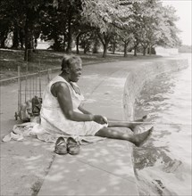 African American woman, seated on ground, fishing, at the Tidal Basin, Washington, D.C.