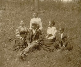African American family posed for portrait seated on lawn