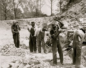 Prisoners breaking up rocks at a prison camp or road construction site