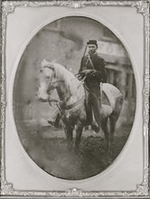 Unidentified African American soldier seated on horseback, facing left.