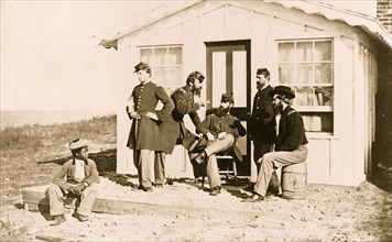 Five Civil War soldiers gathered on dirt porch outside home, African American youth seated near them