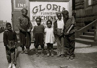 African American Children in front of a sign selling kitchenettes