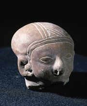 Clay head with eyes and ornaments.