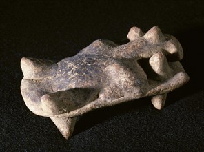 Clay figurine. It depicts a man lying on a bed.