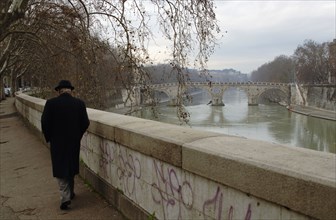 Old man walking along the river Tiber.
