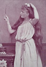 girl with very long hair looks in a hand mirror
