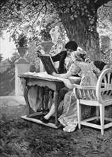 young couple with a book in the garden under a linden tree