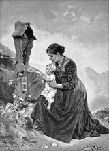 Mother and baby at the memorial cross of the father who died in an accident in the mountains