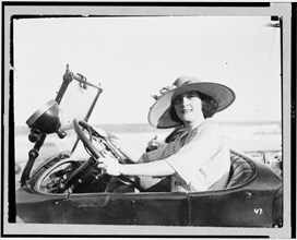 Portrait of 1920s era woman driving an automobile.