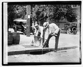 1920's - Pouring whiskey into a sewer during Prohibition.