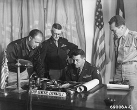 Major Gen. Claire Chennault of the US Air Force (seated) studies aerial maps of Southern China as fellow officers look on.