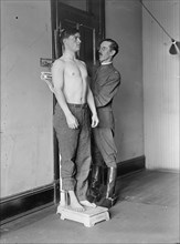Army doctor conducting a physical exam on a young World War I recruit. Washington, DC, 1917.