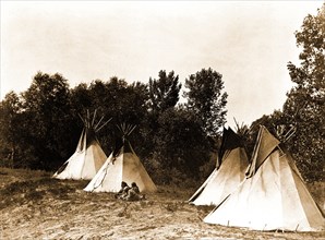Edward S. Curtis Native American Indians - An Assiniboin camp containing four tepees with Indians seated on ground circa 1908.