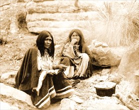 Edward S. Curits Native American Indians - Two Apache Indian women at campfire, cooking pot in front of one circa 1903.