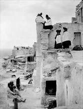 Edward S. Curtis Native American Indians - Photo shows Hopi women seated and standing on pueblo buildings circa 1906.