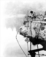 Edward S. Curits Native American Indians - Hupa Indian on platform over water using fishing net circa 1923.