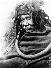 Edward S. Curits Native American Indians - Half-length portrait of Nakoaktok man, facing left, wearing cedar root ceremonial loop circa 1910.