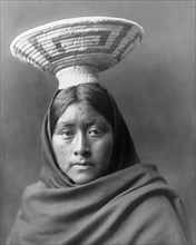 Edward S. Curits Native American Indians - Papago Indian, Luzi, head-and-shoulders portrait, facing front, with a basket tray on her head circa 1907.