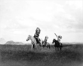 Edward S. Curits Native American Indians - Three Sioux Indians on horseback on plains with rock formations in background circa 1905.