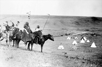 Edward S. Curits Native American Indians -  Four Atsina Indians on horseback overlooking tepees in valley beyond circa 1908.