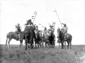 Edward S. Curtis Native American Indians - Several Atsina warriors on horseback some with feathered staffs and one with a headdress circa 1908.