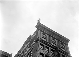 J. Reynolds Acrobat, performing acrobatic and balancing acts on top of building above 9th Street NW in Washington D.C. circa 1917.