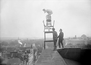 J. Reynolds Acrobat, performing acrobatic and balancing acts on top of building above 9th Street NW in Washington D.C. circa 1917.