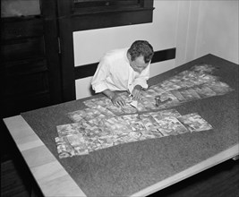 Map maker fitting together photos for the final map circa 1937.